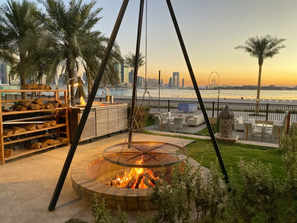 Top 5 Outdoor Amenities For HOAs & Condos 1 Firepit in beautiful setting with palm trees and sunset over water in the background. HOA outdoor amenities
