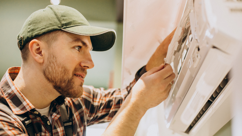 The 3 Rs of HOA Maintenance: Responsibilities, Risks & Recommendations 1 An image of a white man performing HOA Maintenance, fixing an air conditioner.