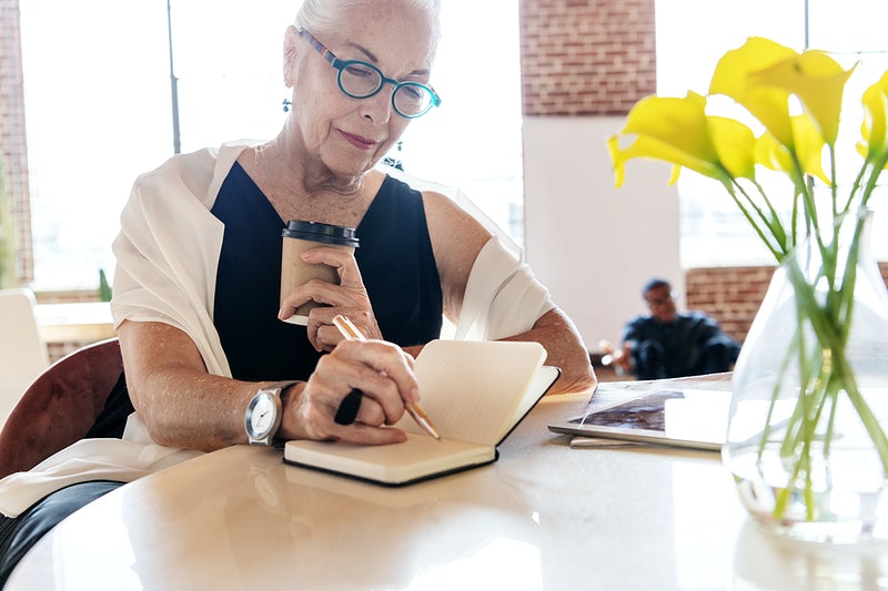 A Guide To Creating A Stellar Condo Association Newsletter 2 Older woman holding a coffee writing in a notebook - condo association newsletter